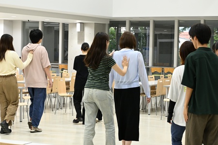 目を瞑った相手の背中を押して歩く様子