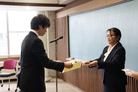 小林学生部長から表彰される学生活動奨励賞を受賞した学生たち