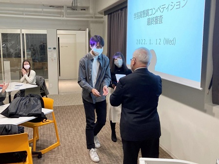 戸部 順一学長より第1位優秀賞を受賞する山重・加藤ゼミ合同チーム代表